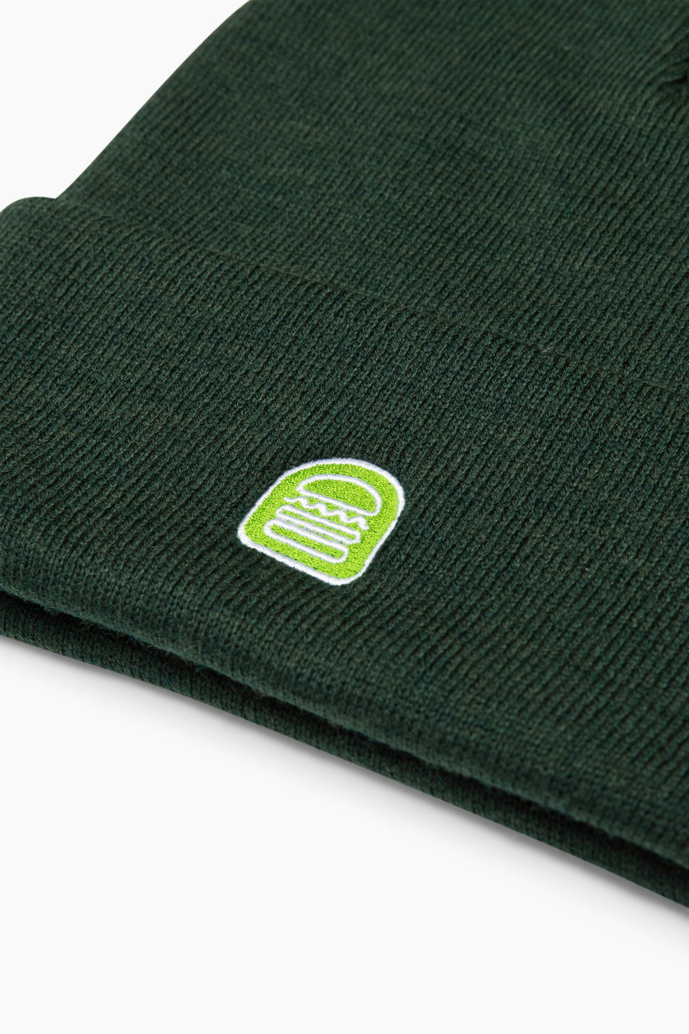 Closeup image of the green beanie that shows the light green embroidered Shake Shack logo