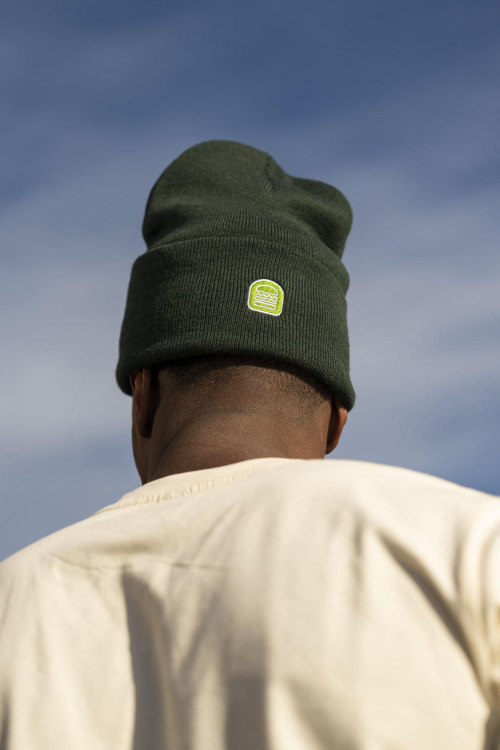 Man outside wearing green Shake Shack beanie with logo facing backwards