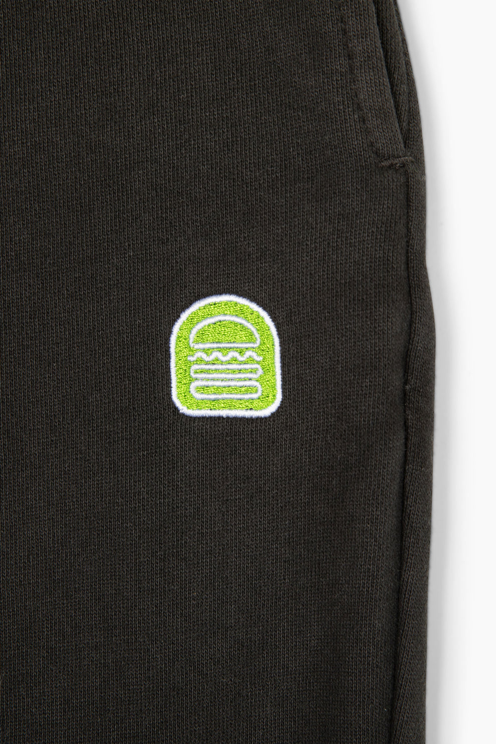 Closeup of the embroidered Shake Shack logo on the left pant leg